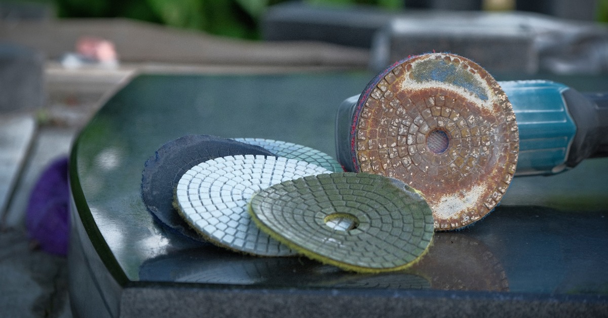 A handheld polishing tool sits on a surface outside. The polisher sits next to a diamond polisher pad.